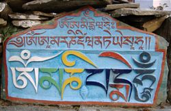 A mani stone carved with the om mani padme hum mantra, and two other mantras including the Amitabha mantra